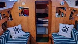 Un interior acogedor con dos camas a rayas, una pequeña zona de estar y una ventana.