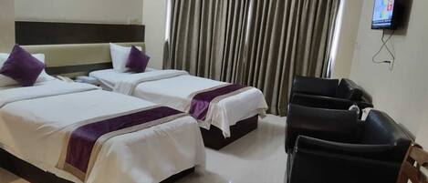 A hotel room with two beds, a TV, and a seating area.