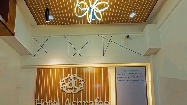 A hotel reception area with a wooden ceiling, a modern chandelier, and a sign reading "Hotel Ashrafee". - Hotel Ashrafee (Dhaka)