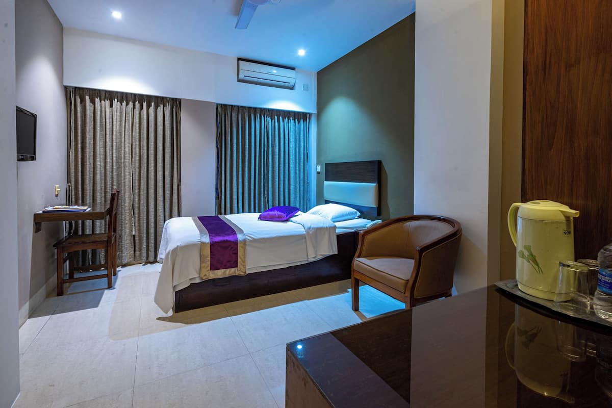 A hotel room with a bed, a desk, a chair, and a coffee maker.