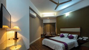 A hotel room with a bed, bedside table, lamp, ceiling fan, and a view of the hallway. - Hotel Ashrafee (Dhaka)