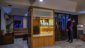 A reception desk with a wooden finish, a clock, and a glass partition. - Hotel Ashrafee (Dhaka)