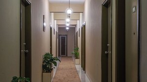A hallway with a carpeted floor, doors on both sides, and a light fixture above. - Hotel Ashrafee (Dhaka)