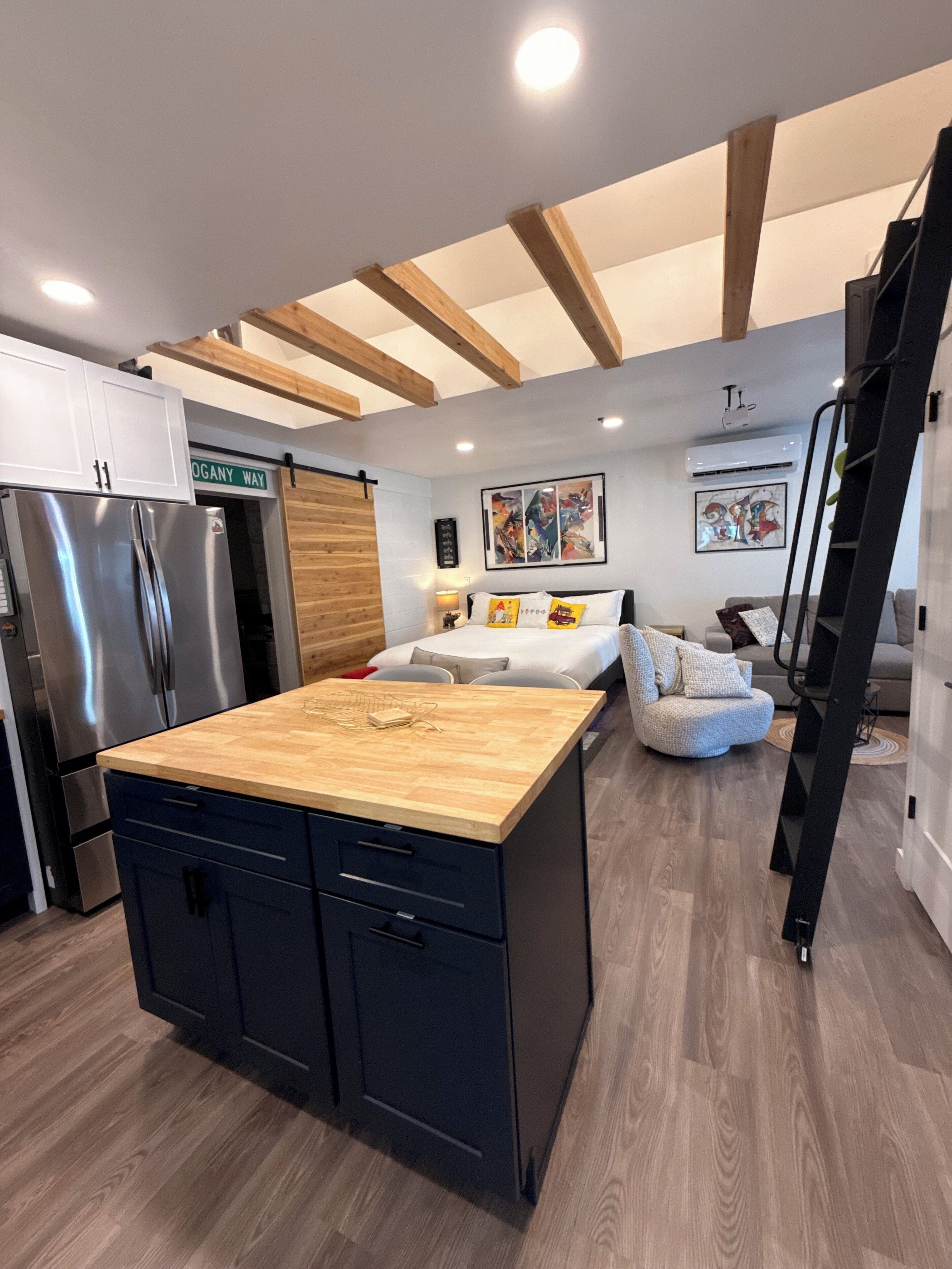 A modern kitchen with a central island, a refrigerator, and a dining area with a sofa and a coffee table.