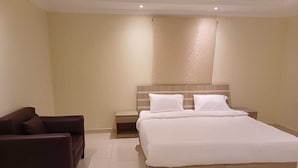 A hotel room with a large bed, a nightstand, a chair, and a wall-mounted headboard. - Al Tawfeeg Hotel Azizyah (Makkah)