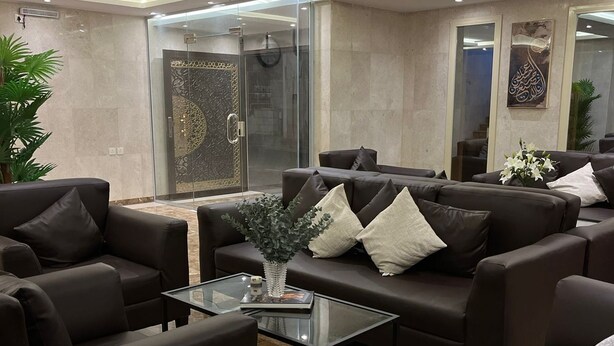 A modern lounge area with leather sofas, a glass coffee table, and a decorative vase. - Al Tawfeeg Hotel Azizyah (Makkah)