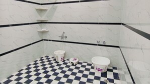 A bathroom with a checkered floor, white and black walls, and a small window. - Hasuli Hotel  (Ukhimath)