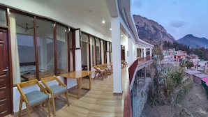 A hotel with a balcony overlooking a mountainous landscape. - Hasuli Hotel  (Ukhimath)