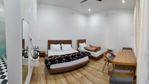 A modern hotel room with a large bed, a wooden table, and a view of the mountains. - Hasuli Hotel  (Ukhimath)