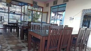 A dining area with a patterned floor, wooden chairs, and a glass-top table. - Hasuli Hotel  (Ukhimath)