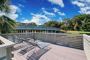 A wooden deck with metal chairs and a bridge structure.