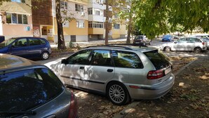 A parking lot with several cars, including a silver station wagon and a blue car. - Apartment for guests Iva (русе)