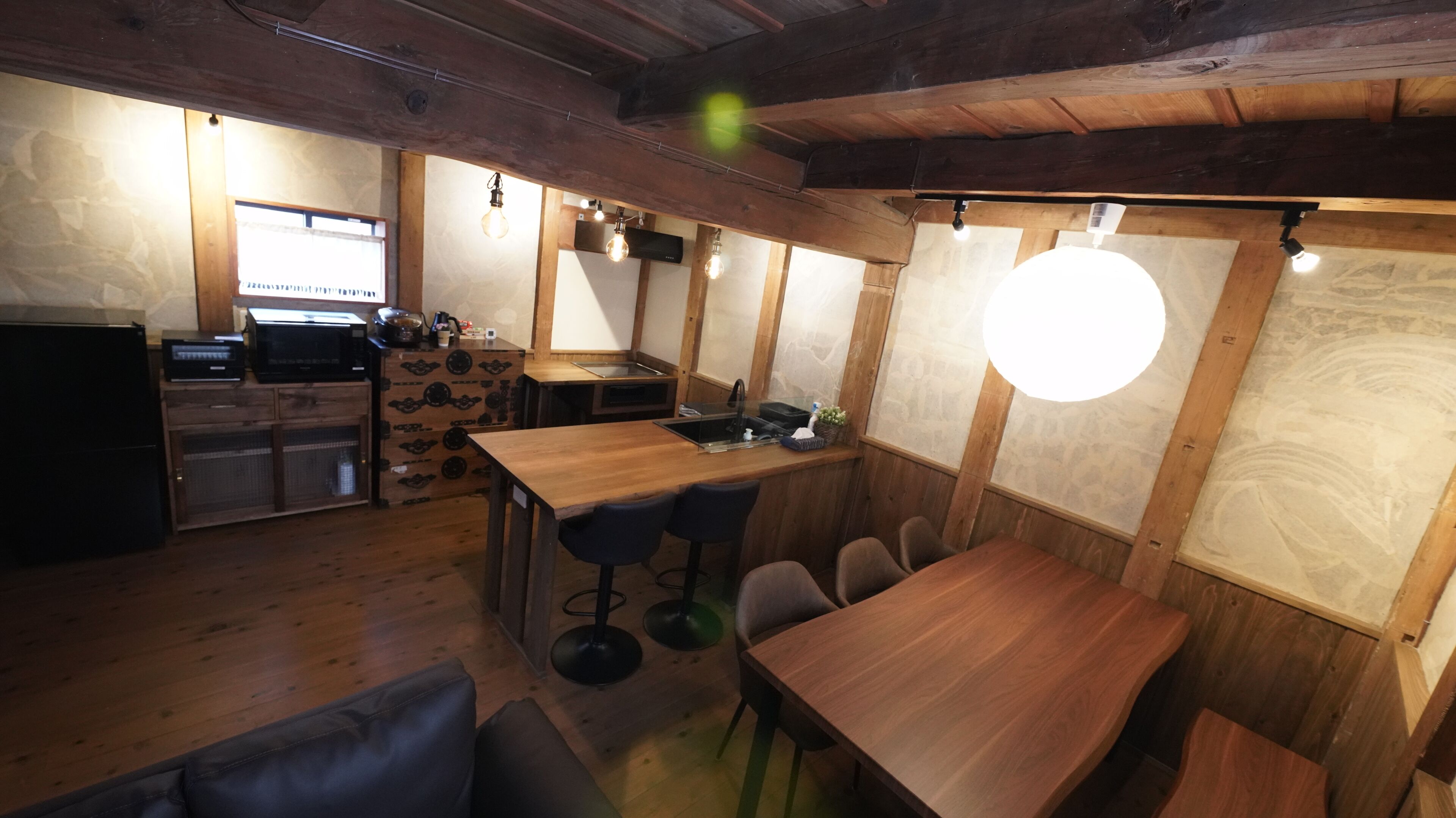 A rustic wooden interior with a bar area, seating, and a kitchen.