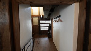 A narrow hallway with wooden flooring, a metal railing, and a wooden door with a window. - FR1 Kominka hotel Fukunokura (Nishiaizu-machi)