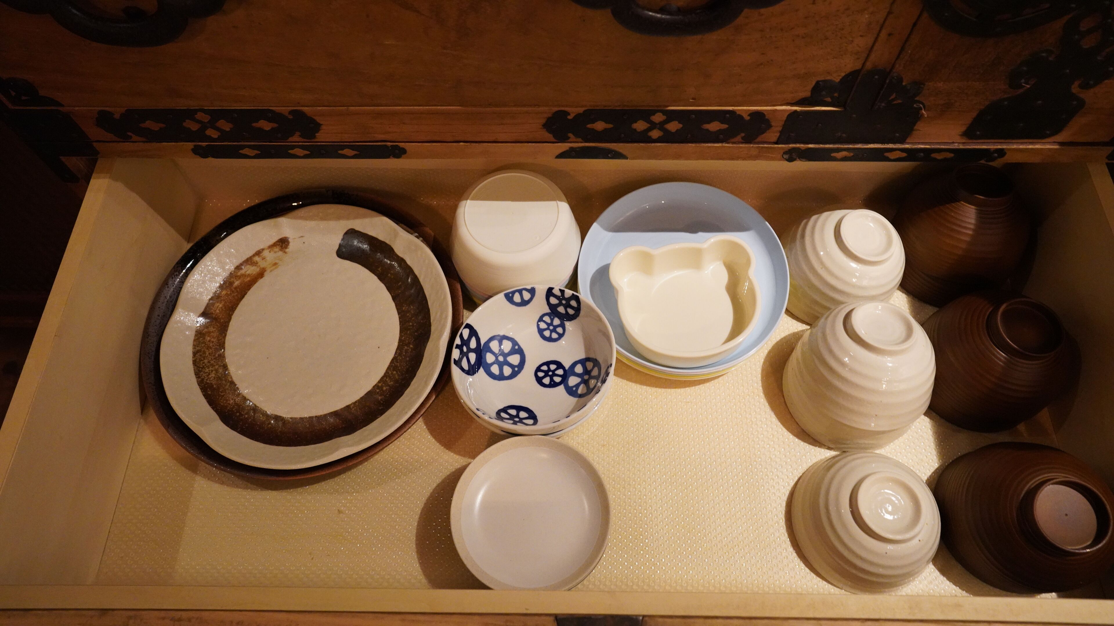 A wooden chest with various ceramic items including plates, bowls, and vases.