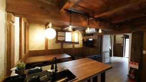 A wooden interior with a kitchen area, including a sink, a dining table, and hanging light fixtures. - FR1 Kominka hotel Fukunokura (Nishiaizu-machi)