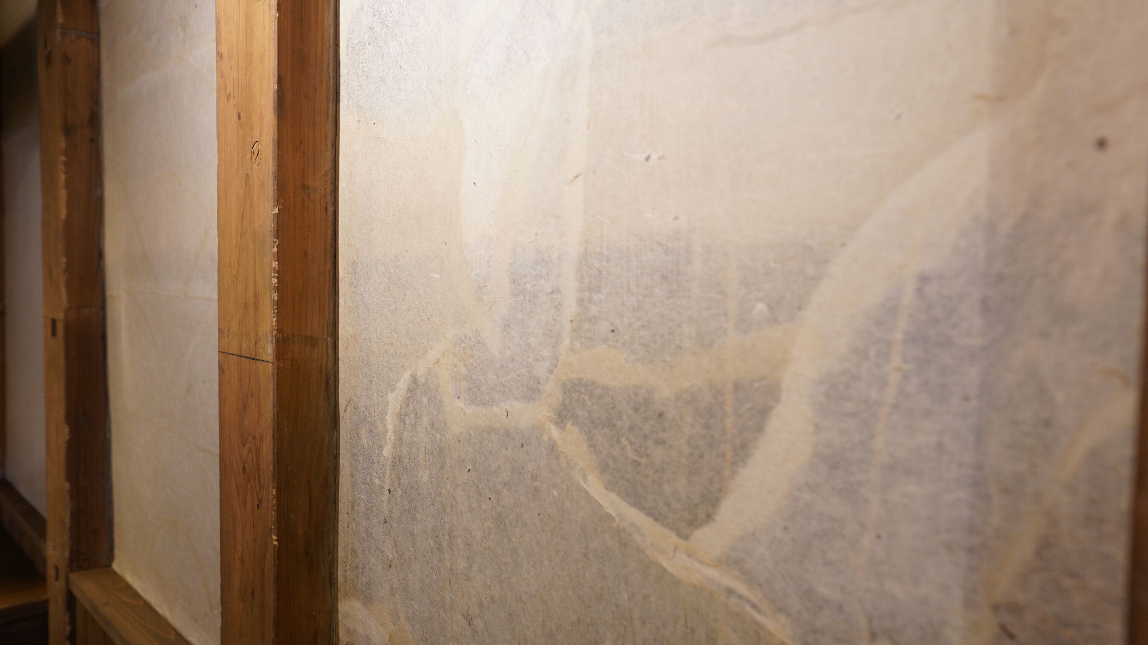 A close-up of a wall with visible wooden framing and a textured surface.
