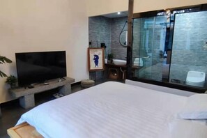 A modern hotel room with a bed, a television, a bathroom with a glass shower enclosure, and a small seating area. - Baiyangdian Weinan Hotel (Anxin)