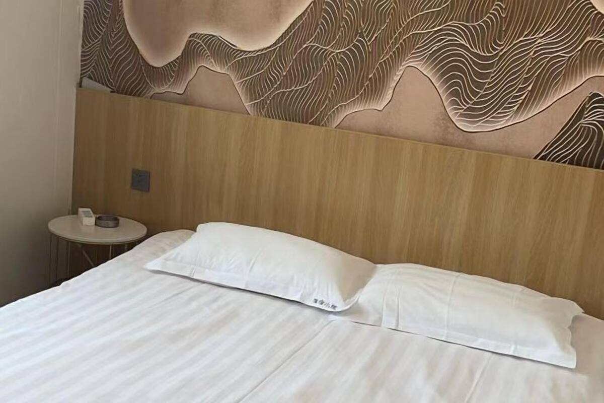 A hotel room with a bed, a round side table, and a textured wall design.