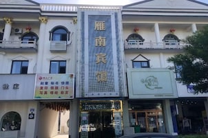 A building with a prominent vertical sign, multiple windows, and a storefront with signage.