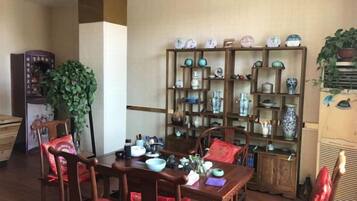 A dining area with a wooden table and chairs, surrounded by shelves with decorative items.