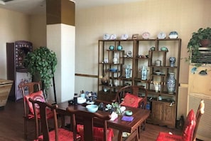 Un comedor con mesa y sillas de madera, rodeado de estantes con objetos decorativos.