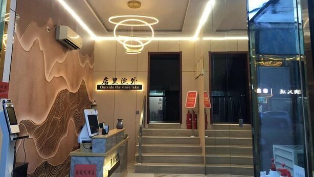 L’entrée d’un hôtel au design moderne, comprenant un comptoir d’accueil, un escalier et un panneau indiquant « Accès au lac depuis l’extérieur du magasin ».