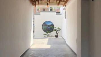 A narrow corridor with a concrete floor, a circular wall art, and a potted plant.