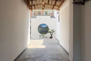 A narrow corridor with a concrete floor, a circular wall art, and a potted plant. - Baiyangdian Weinan Hotel (Anxin)