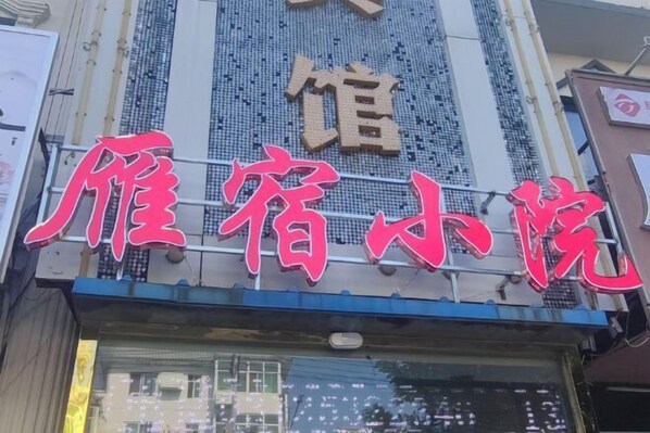 A hotel sign with large red characters and a smaller sign above it.