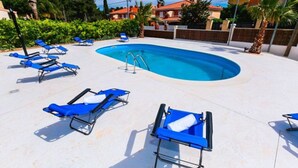 Une piscine avec des chaises longues bleues et une eau d’un bleu cristallin.