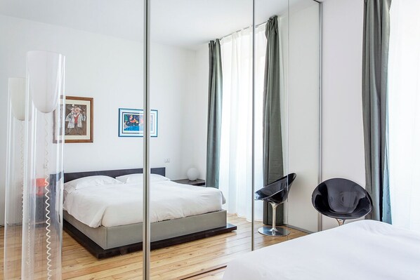 Una habitación de hotel moderna con cama, mesita de noche y una silla.