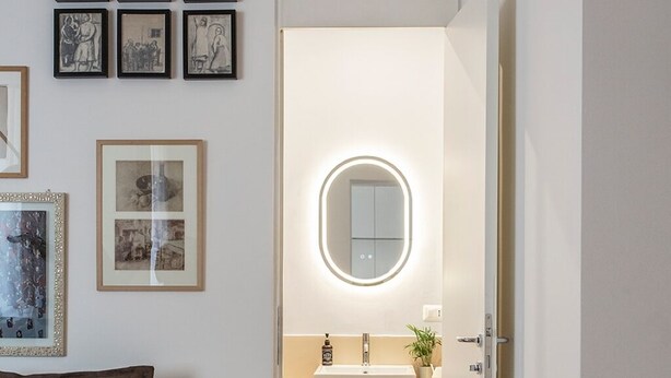 Un baño moderno con un espejo redondo, un lavabo y cestas de mimbre.
