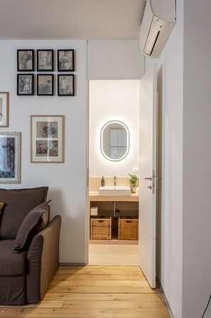Un baño moderno con un espejo redondo, un lavabo y cestas de mimbre.