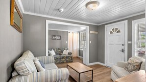 A living room with a sofa, a coffee table, and a door labeled "MYTHIC BEACH". - Holly Haven 1706: 5  BR, 3.5  BA House in North Myrtle Beach, Sleeps 16 (North Myrtle Beach)