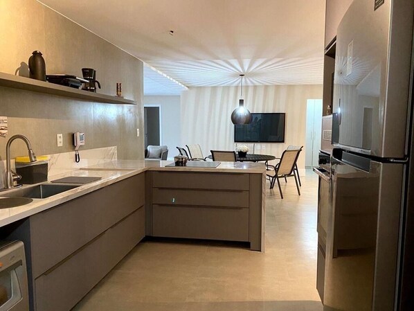A modern kitchen with a central island, built-in appliances, and a dining area with a TV.