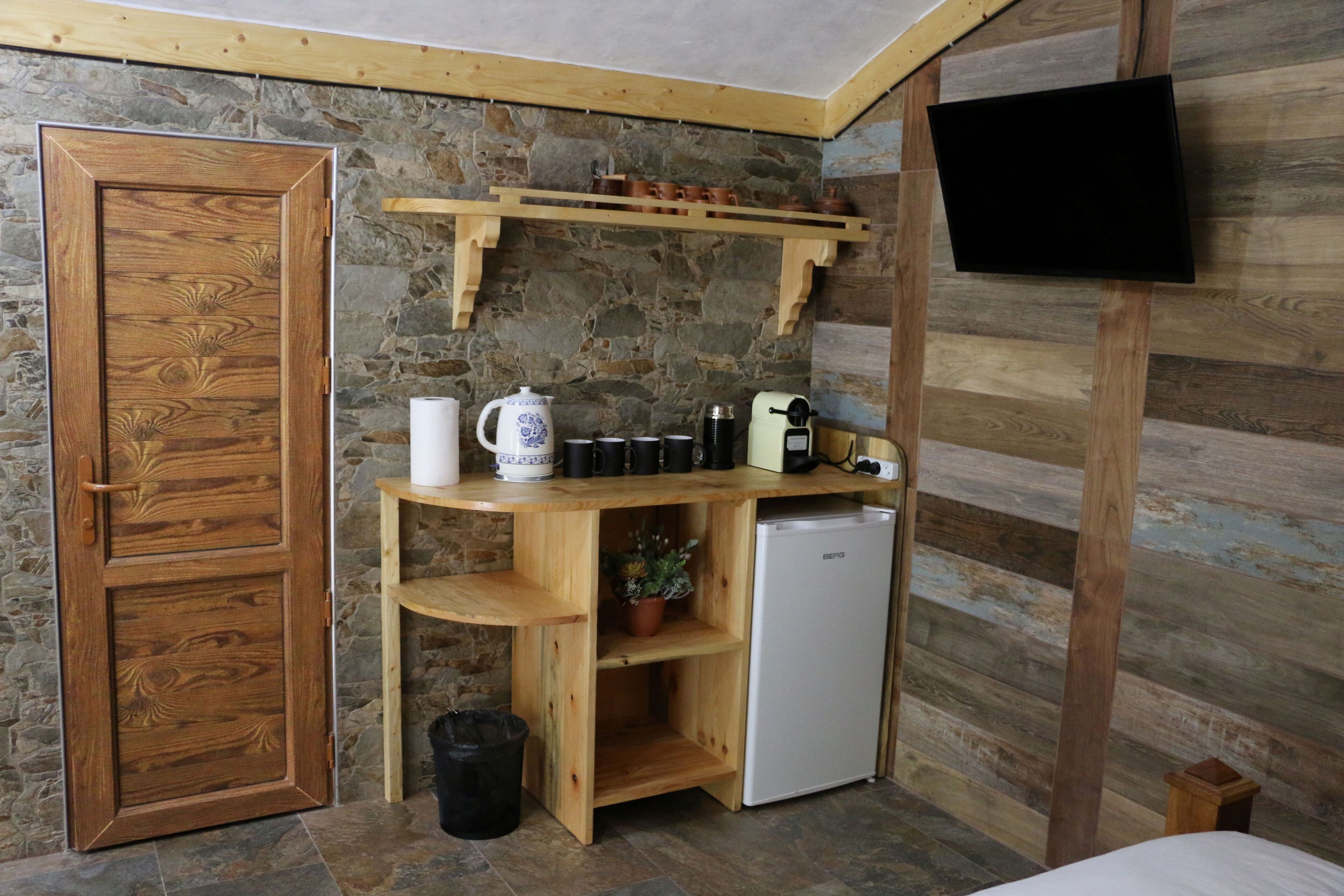 A compact kitchen with a wooden counter, a coffee maker, and a small refrigerator.