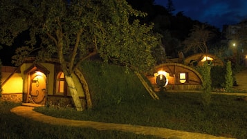 Un edificio de estilo rústico tipo casa del árbol, con puerta y ventanas de madera, rodeado de vegetación.