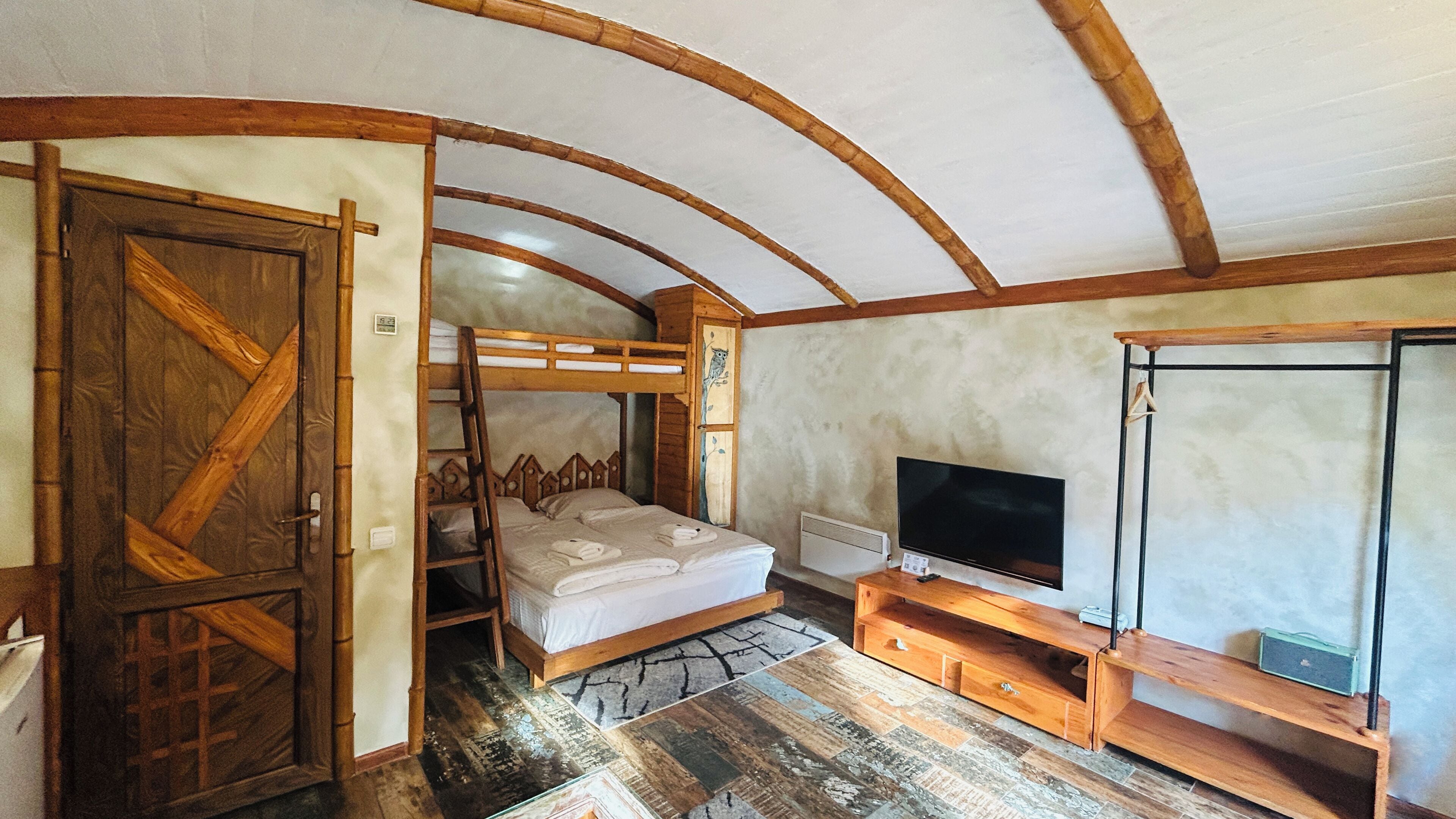 Quarto com beliche, televisão e guarda-roupa de madeira.