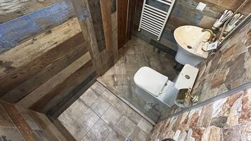 Een badkamer met een houten vloer, een wit toilet en een wastafel met spiegel.