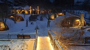 Ένα χιονισμένο τοπίο με αρκετές καλύβες σε σχήμα θόλου, φωτισμένες με ζεστά φώτα.