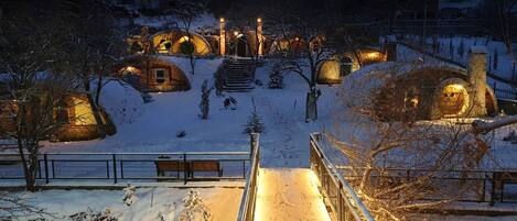 A snow-covered landscape with several dome-shaped cabins illuminated by warm lights.