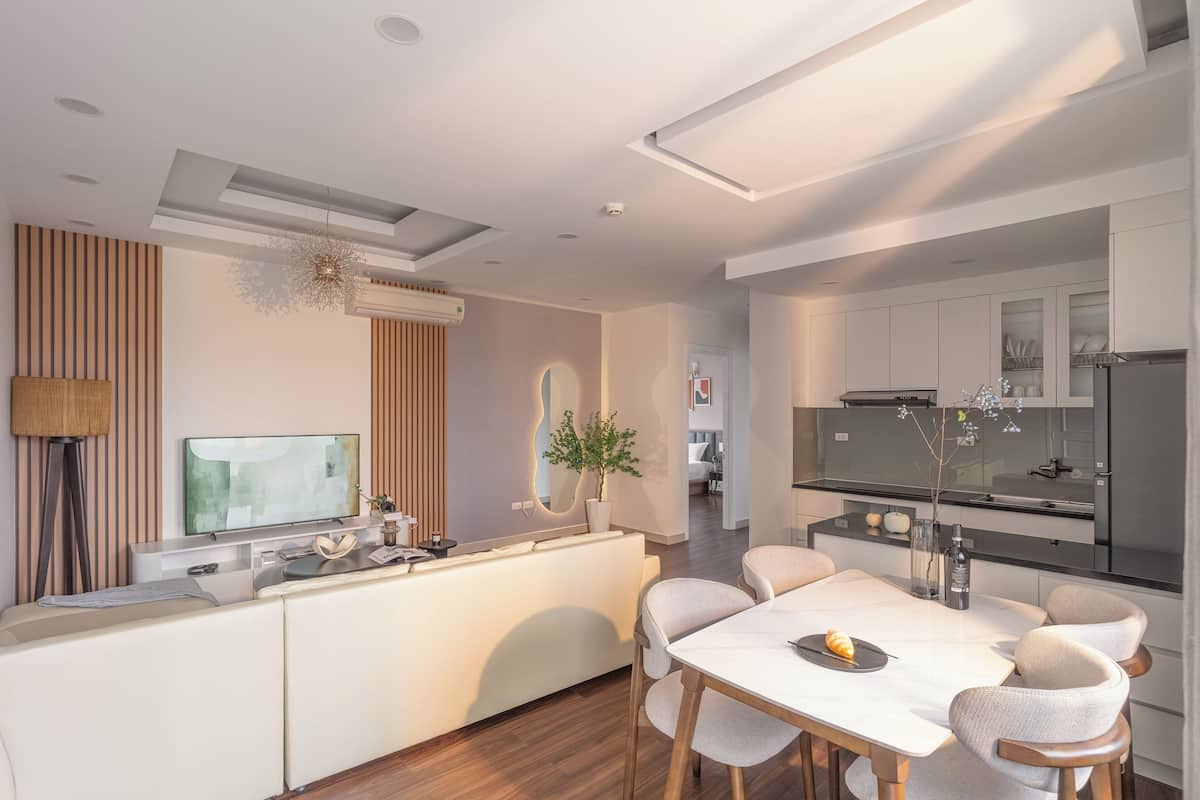 Una cocina moderna con una isla central, electrodomésticos integrados y un comedor con mesa y sillas blancas.