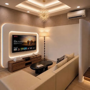 Een moderne woonkamer met een flatscreen televisie, een bank, een salontafel en een vloerlamp.