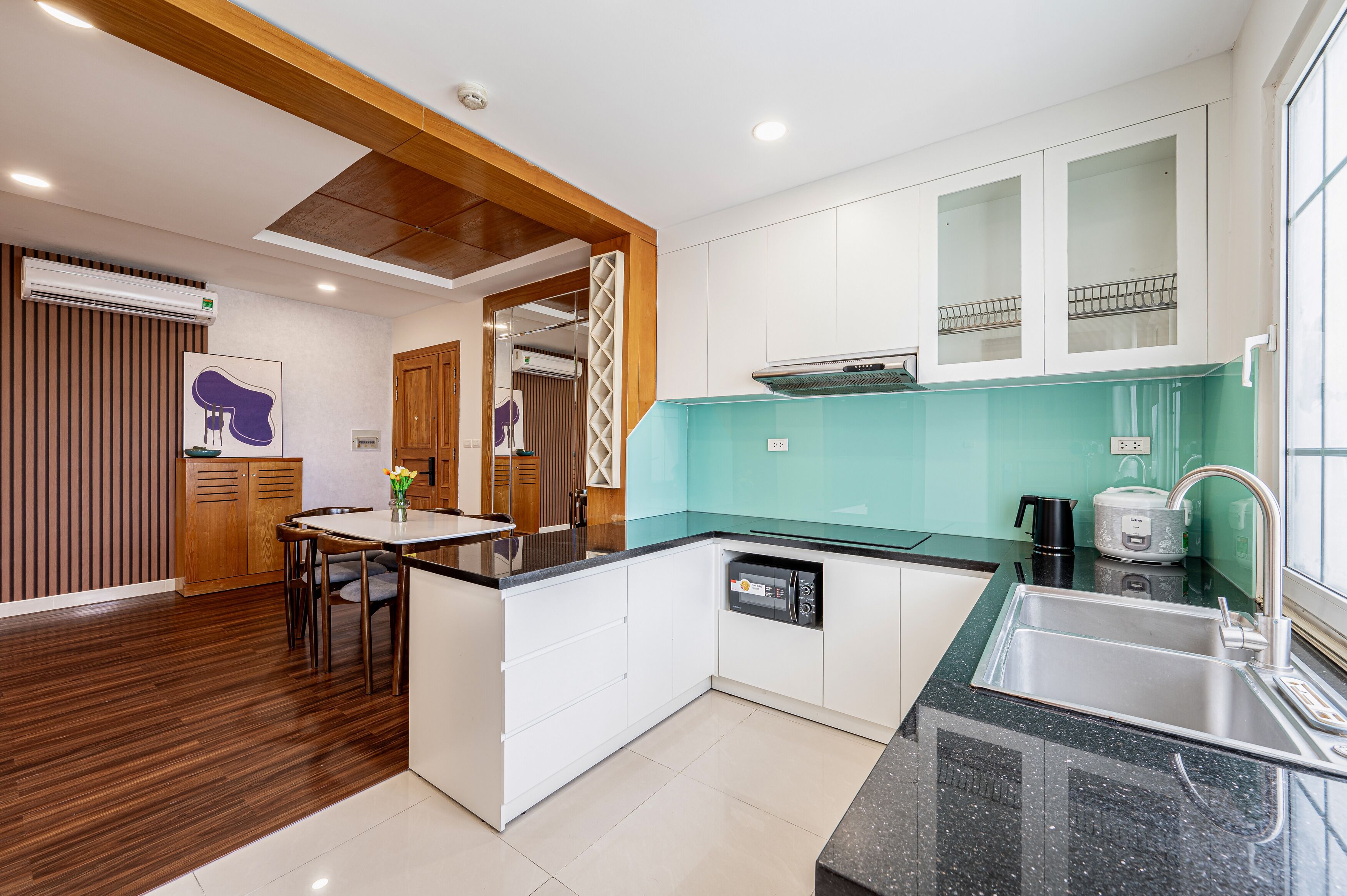 A modern kitchen with a central island, built-in dishwasher, and a large sink.