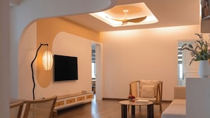 Un salon moderne doté d’un téléviseur à écran plat, de meubles en bois et d’un ventilateur de plafond.