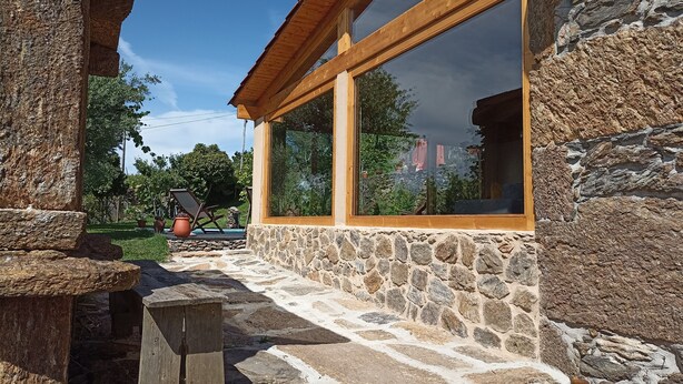 A stone building with large windows and a wooden deck.