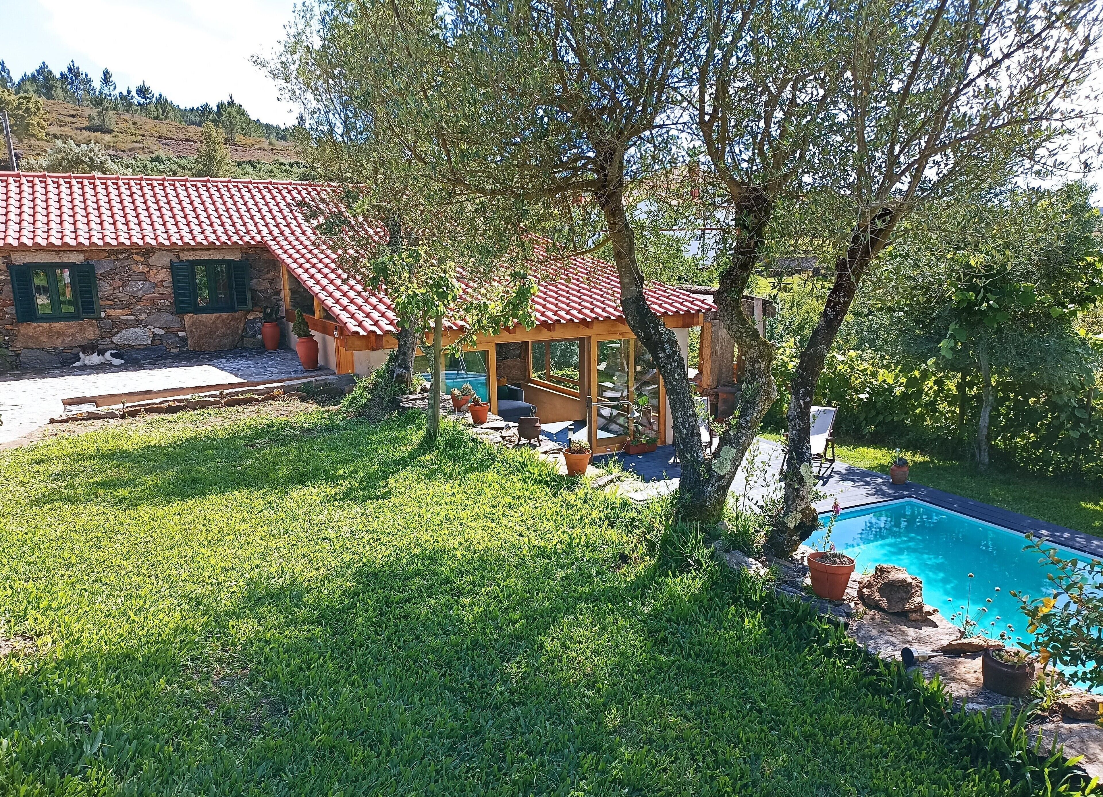 A house with a tiled roof, a swimming pool, and a garden.