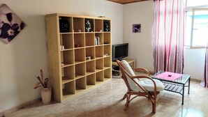 A living room with a wooden bookshelf, a television, a wicker chair, and a small table. - Arguineguin, vacation home directly by the sea, Casa Perchel (Arguineguin)