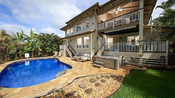 Une maison à deux étages dotée d’une piscine, d’un espace salon extérieur et d’un escalier menant à un balcon.
